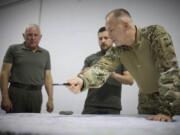 In this photo provided by the Ukrainian Presidential Press Office, Ukrainian President Volodymyr Zelenskyy, center, Commander-in-Chief Oleksandr Syrsky, right, look at a map during their visit to Sumy, Ukraine, Thursday, Aug. 22, 2024.