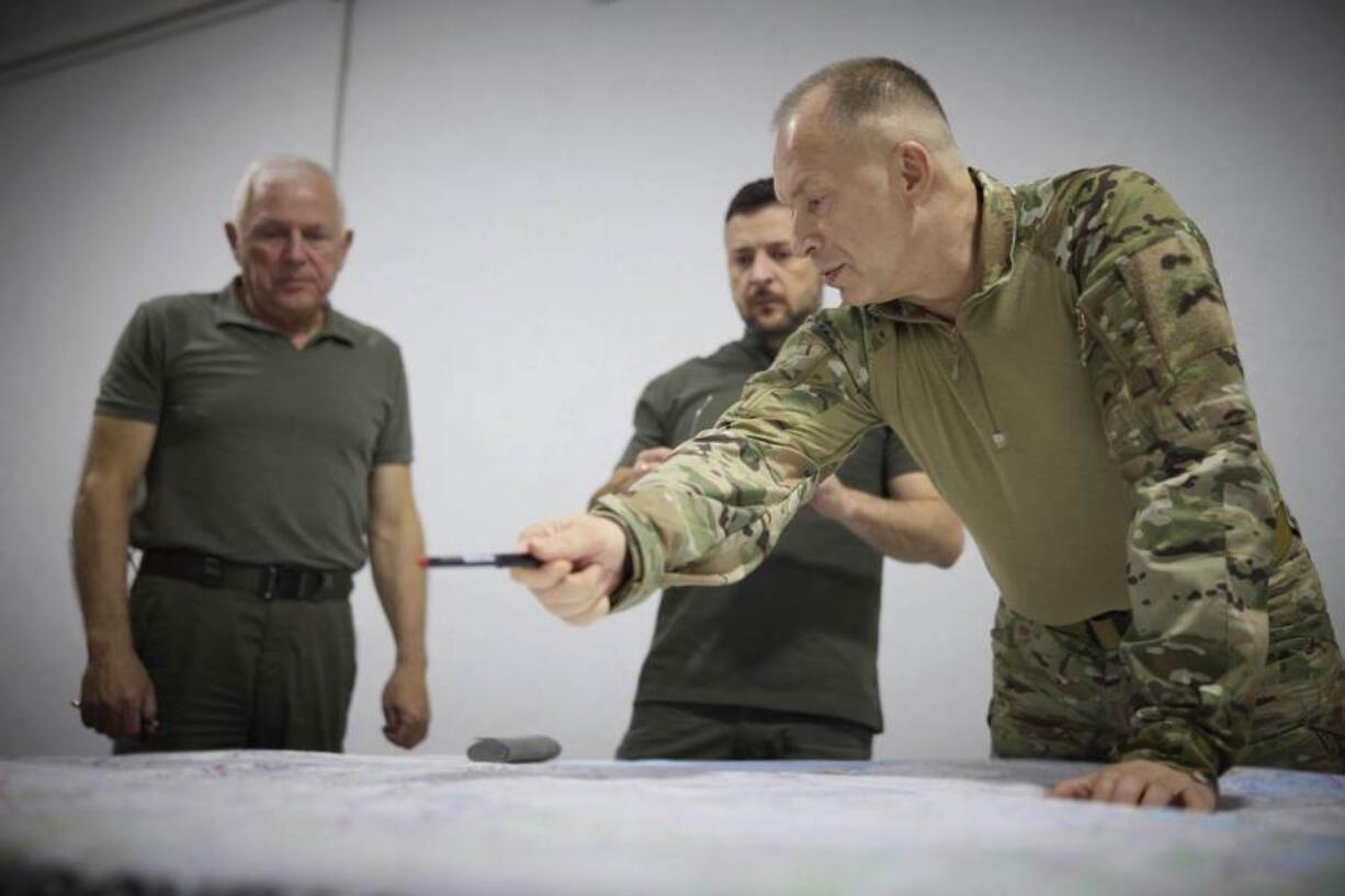 In this photo provided by the Ukrainian Presidential Press Office, Ukrainian President Volodymyr Zelenskyy, center, Commander-in-Chief Oleksandr Syrsky, right, look at a map during their visit to Sumy, Ukraine, Thursday, Aug. 22, 2024.