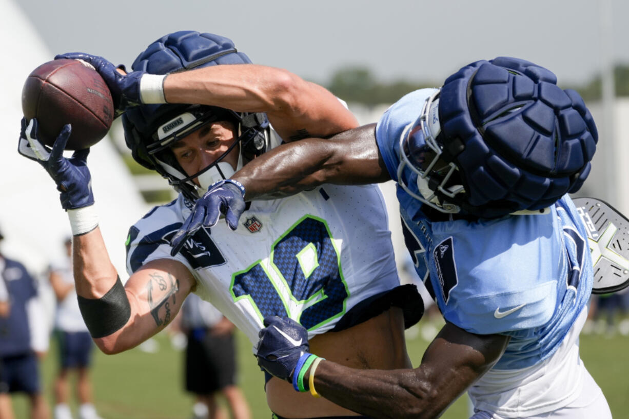 Seattle Seahawks wide receiver Jake Bobo (19) makes a catch over Tennessee Titans cornerback Roger McCreary, right, during an NFL joint football training camp practice Thursday, Aug. 15, 2024, in Nashville, Tenn.