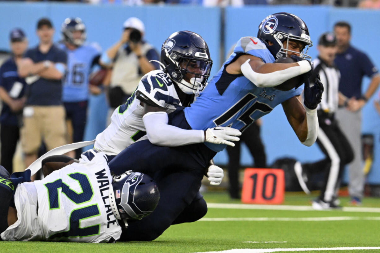 Tennessee Titans wide receiver Nick Westbrook-Ikhine (15) scores on a 15-yard touchdown reception between Seattle Seahawks safety K&rsquo;Von Wallace (24) and cornerback D.J. James (29) during the first half of an NFL preseason football game, Saturday, Aug. 17, 2024, in Nashville, Tenn.