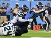 Tennessee Titans wide receiver Nick Westbrook-Ikhine (15) scores on a 15-yard touchdown reception between Seattle Seahawks safety K&rsquo;Von Wallace (24) and cornerback D.J. James (29) during the first half of an NFL preseason football game, Saturday, Aug. 17, 2024, in Nashville, Tenn.