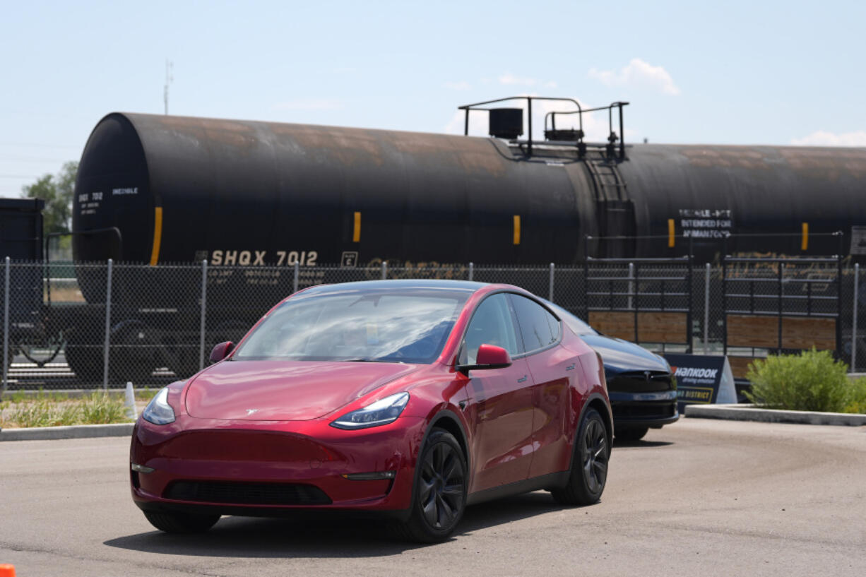 FILE - Drivers guide 2024 a Tesla Model 3 sedan and Model X utility vehicle, rear, along a test track at the Electrify Expo in The Yards on July 14, 2024, in north Denver.