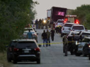 FILE - Police and other first responders work the scene where officials say dozens of people have been found dead and multiple others were taken to hospitals with heat-related illnesses after a tractor-trailer containing suspected migrants was found on June 27, 2022, in San Antonio.