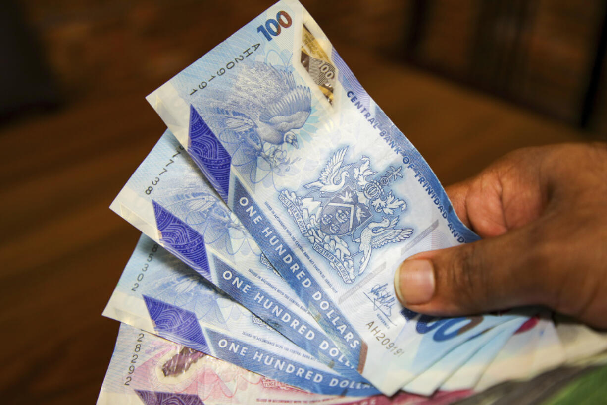 A vendor holds a handful of Trinidad and Tobago dollars, in Port-of-Spain, Trinidad and Tobago, Tuesday, Aug. 20, 2024. Prime Minister Keith Rowley announced Sunday, Aug. 18, 2024, the country is redrawing the island&rsquo;s coat of arms to remove references to European colonization and that Christopher Columbus&rsquo; three ships will be replaced with the steelpan, a popular percussion instrument.