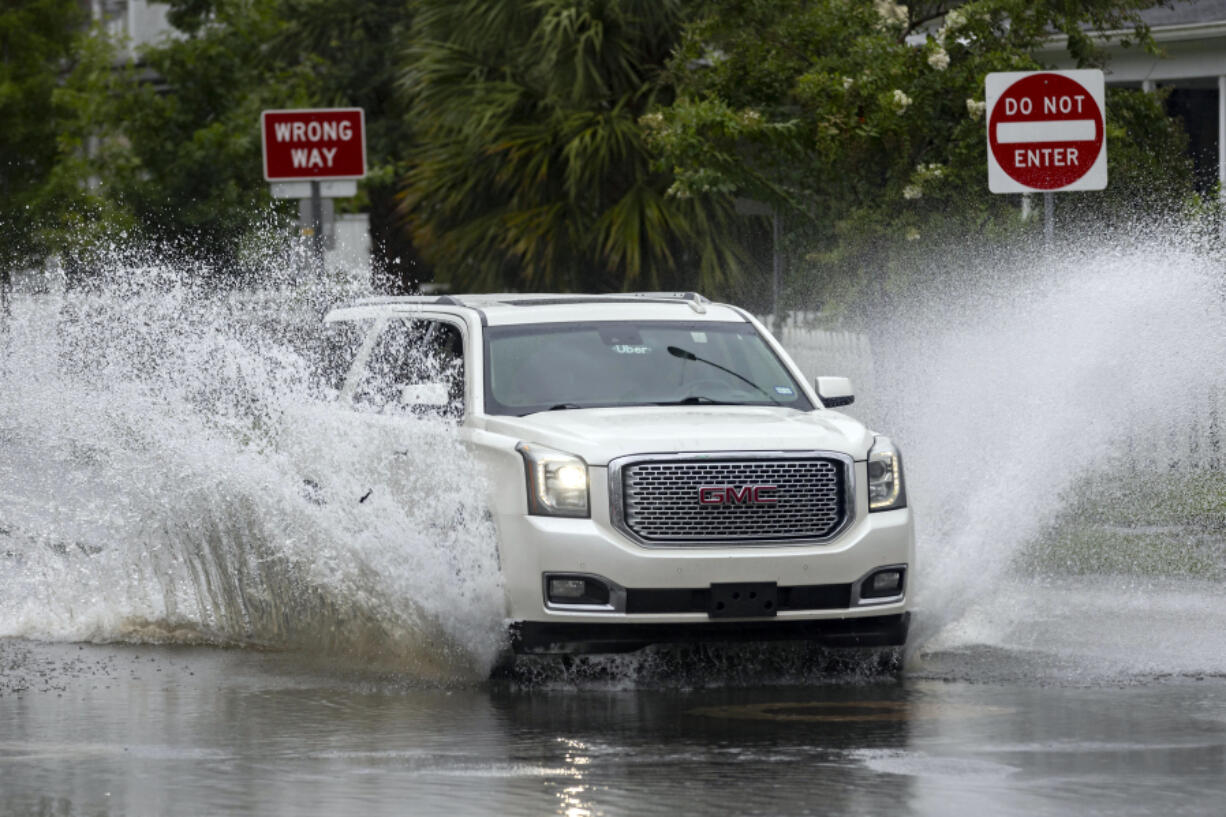 An SUV plows through a flooded street after heavy rain from Tropical Storm Debby, Monday, Aug. 5, 2024, in Savannah, Ga. (AP Photo/Stephen B.