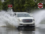 An SUV plows through a flooded street after heavy rain from Tropical Storm Debby, Monday, Aug. 5, 2024, in Savannah, Ga. (AP Photo/Stephen B.