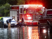 People attach a towline to a stranded vehicle on a flooded street after heavy rain from Tropical Storm Debby, Monday, Aug. 5, 2024, in Savannah, Ga. (AP Photo/Stephen B.