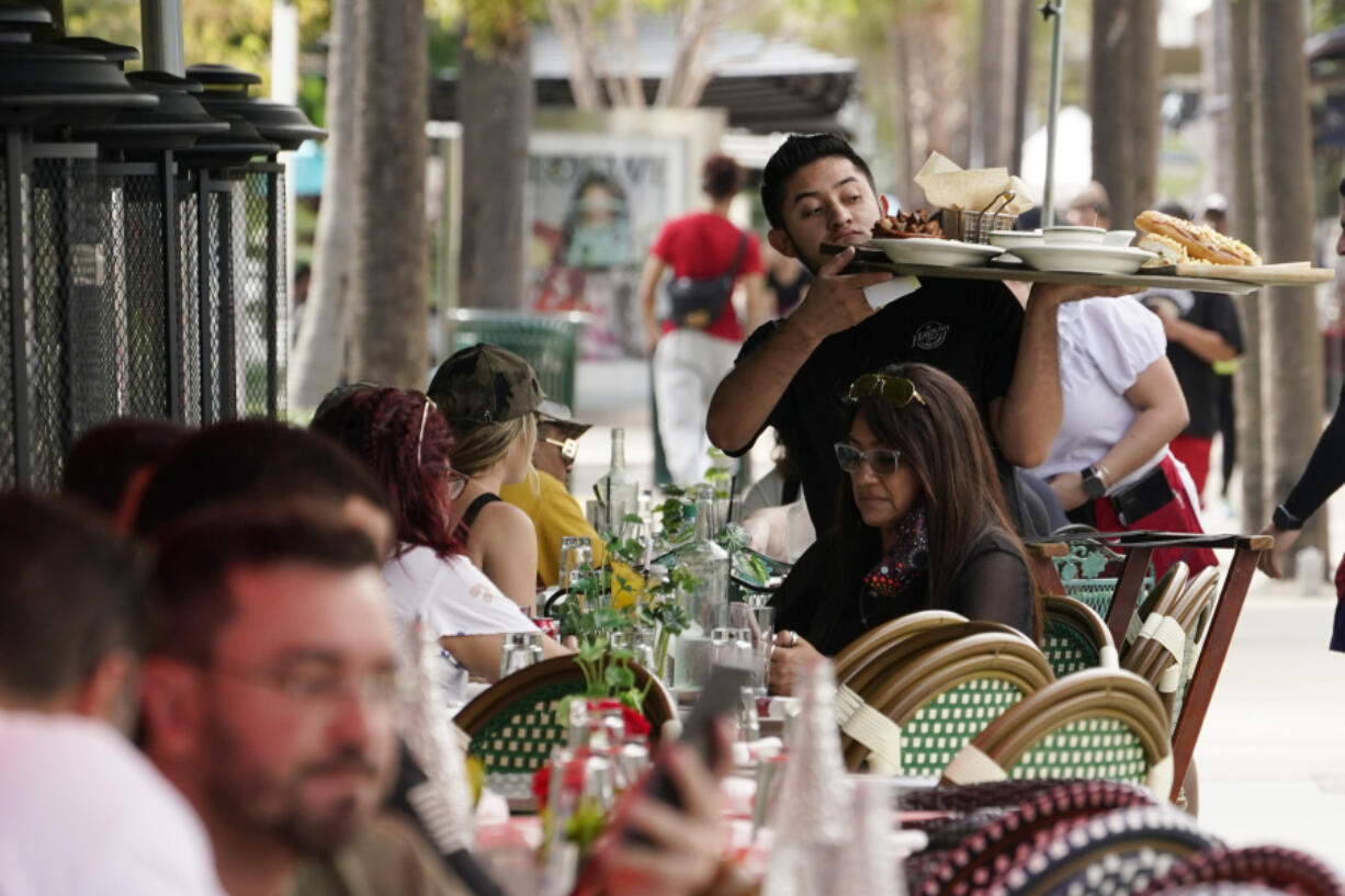 FILE - A waiter delivers food to patrons at a restaurant, Jan. 21, 2022, in Miami Beach, Fla.