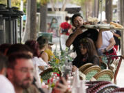 FILE - A waiter delivers food to patrons at a restaurant, Jan. 21, 2022, in Miami Beach, Fla.