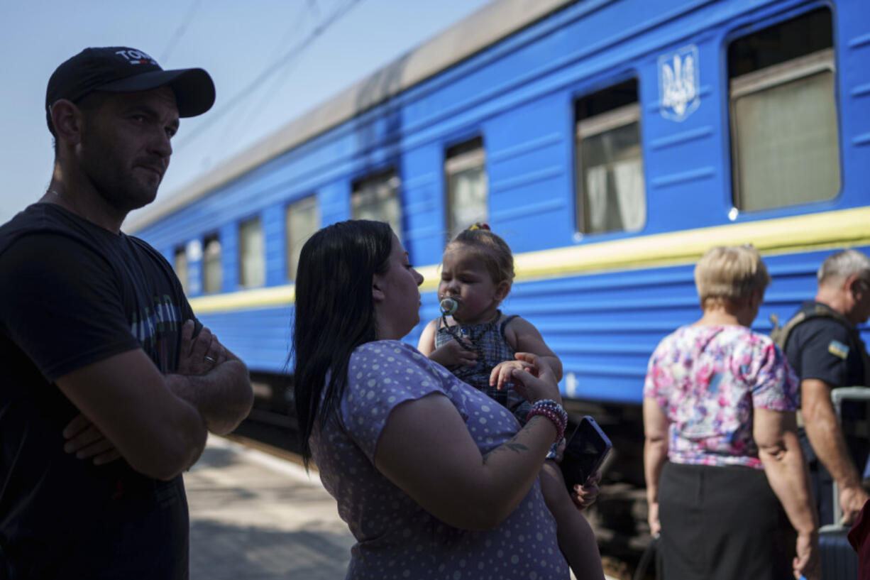 A family stay in line for in evacuation train in Pokrovsk, Donetsk region, Ukraine, Monday, August 19, 2024. Due to the advance of Russian troops, the war affects more and more new settlements to the west of the Donetsk region. Intensive shelling forced people to leave homes.