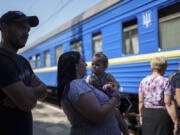 A family stay in line for in evacuation train in Pokrovsk, Donetsk region, Ukraine, Monday, August 19, 2024. Due to the advance of Russian troops, the war affects more and more new settlements to the west of the Donetsk region. Intensive shelling forced people to leave homes.