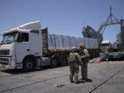 FILE - U.S. Army soldiers stand next to trucks arriving loaded with humanitarian aid at the U.S.-built floating pier Trident before reaching the beach on the coast of the Gaza Strip, June 25, 2024.