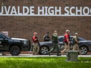 FILE - Law enforcement personnel walk outside Uvalde High School after shooting a was reported earlier in the day at Robb Elementary School, Tuesday, May 24, 2022, in Uvalde, Texas.