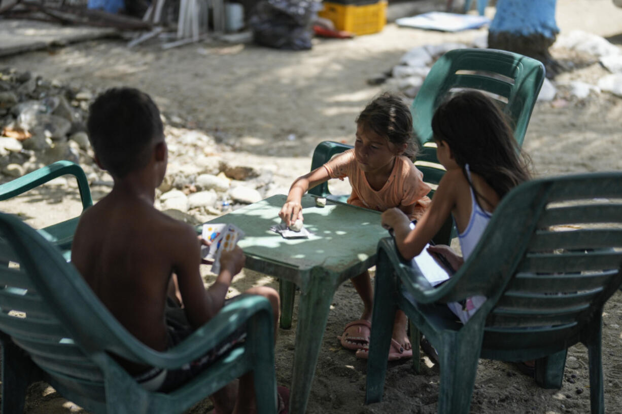 Children play a card game on a public beach in La Guaira, Venezuela, Friday, July 26, 2024.