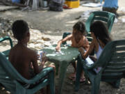 Children play a card game on a public beach in La Guaira, Venezuela, Friday, July 26, 2024.