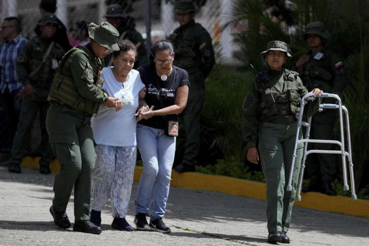 Military personnel help assist an elderly voter during the presidential election in Caracas, Venezuela, Sunday, July 28, 2024.