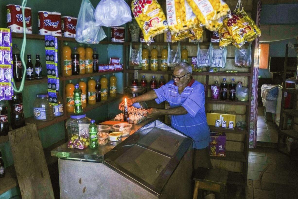 A man lights a candle in his shop during a blackout in Caracas, Venezuela, on Friday.