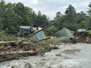 FILE - Trees and debris sit next to a damaged home after flooding in Lyndonville, Vt., Tuesday, July 30, 2024.