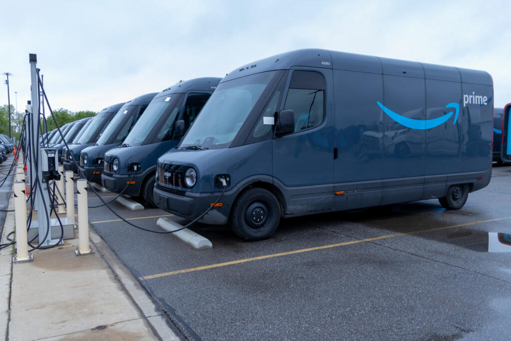 Electric delivery vans lined up at a charging station, highlighting the shift towards sustainable transportation.