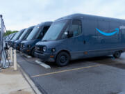 Electric delivery vans lined up at a charging station, highlighting the shift towards sustainable transportation.