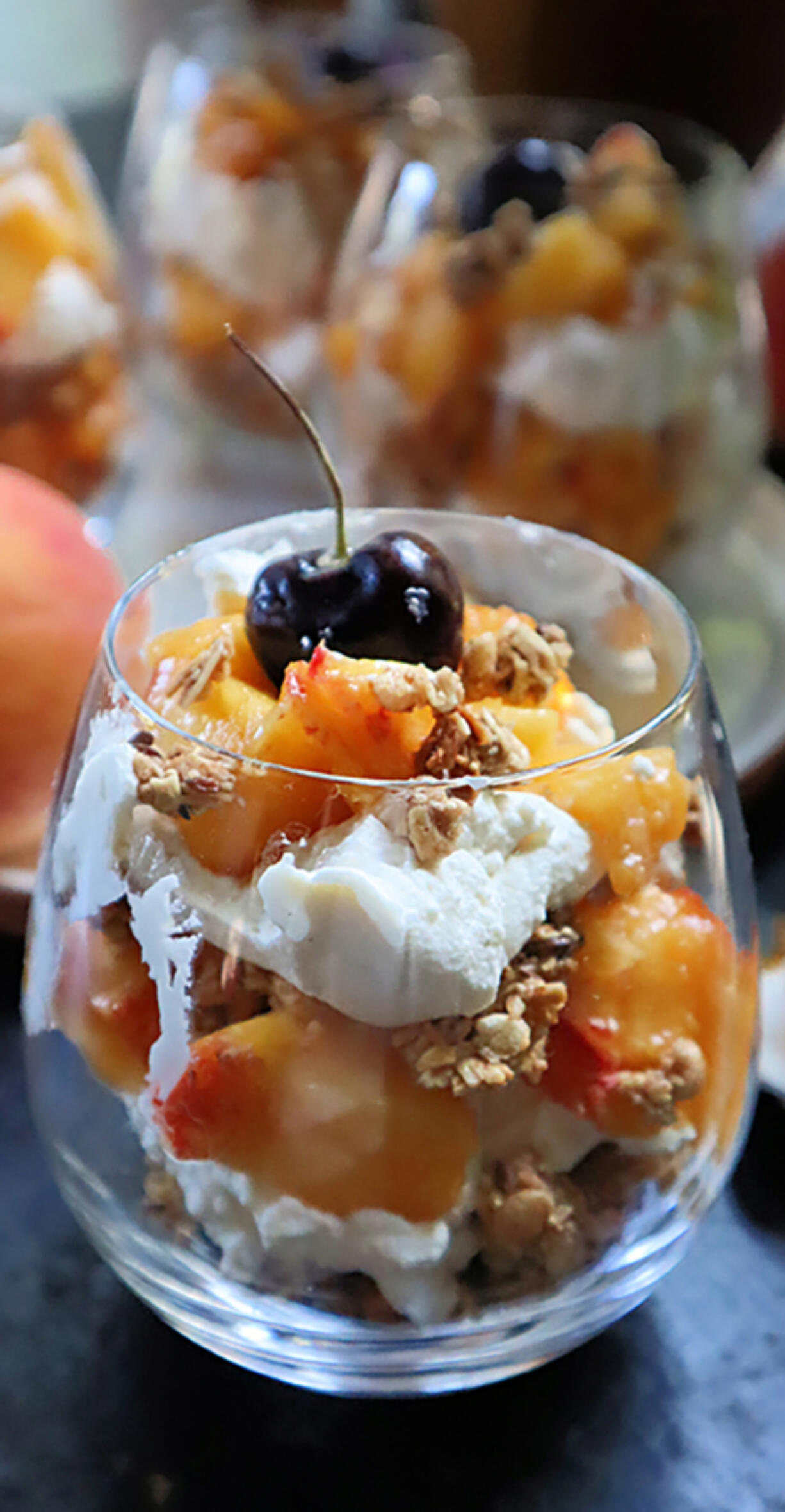 Individual peach parfaits layered with homemade granola and with spiced whipped cream are a crowd-pleasing dessert.