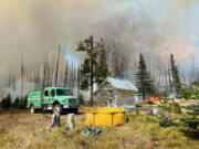 The Morrison Shelter was wrapped in protective fabric on Friday and operations reduced the amount of fuel near the shelter before the approaching edge of the main fire reached the area on Monday. An engine from the Mount Hood National Forest assisted. In the foreground, a yellow portable water tank is available to provide a water source for work in this area.