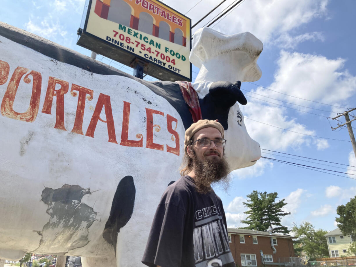 Kevin McCarthy of Momence, Ill., stands Aug. 7 outside Los Portales restaurant in Chicago Heights, Ill., in front of a giant fiberglass cow placed outside of the restaurant on Chicago Road for decades. McCarthy, an advertising giant enthusiast, recently helped track down the fate of a giant fiberglass Frank-n-Stein statue that once stood outside a restaurant in Gary, Ind.