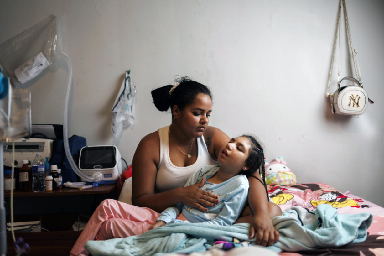 Yamile Perez, 28, holds her daughter Keinymar Avila, 8, while posing for a portrait in their home in the South Shore neighborhood of Chicago on Aug. 7, 2024. Avila has microcephaly &Ccedil;&fnof;&Oacute; a condition where a baby&Ccedil;&fnof;&Ugrave;s head is smaller than normal causing seizures, developmental delays and intellectual disability. (Armando L.