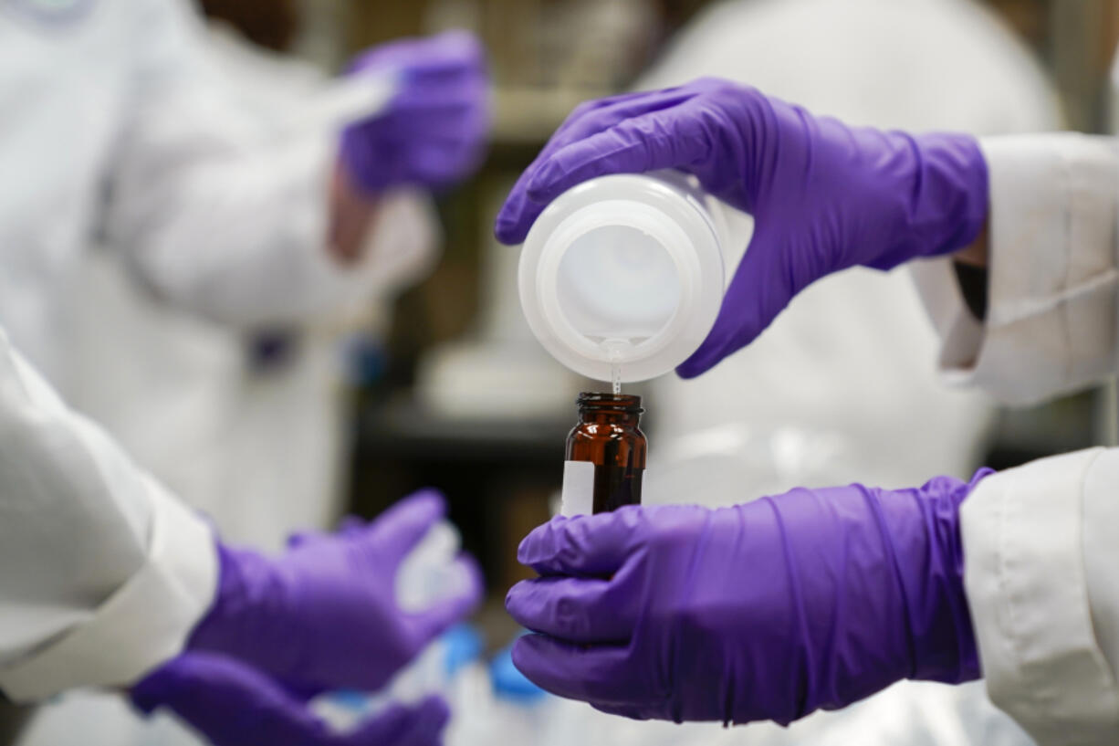 Eva Stebel, water researcher, pours a water sample into a smaller glass container for experimentation as part of drinking water and PFAs research at the U.S. Environmental Protection Agency Center For Environmental Solutions and Emergency Response on Feb. 16, 2023, in Cincinnati. (AP Photo/Joshua A.