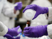 Eva Stebel, water researcher, pours a water sample into a smaller glass container for experimentation as part of drinking water and PFAs research at the U.S. Environmental Protection Agency Center For Environmental Solutions and Emergency Response on Feb. 16, 2023, in Cincinnati. (AP Photo/Joshua A.