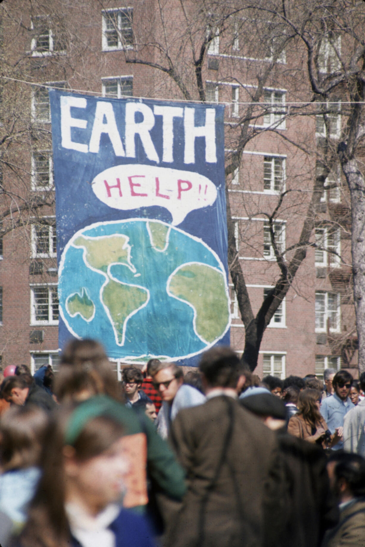 A crowd of people gather near a large poster that shows a speech bubble from planet Earth that reads &quot;Help!!&quot; on the occasion of the first Earth Day conservation awareness celebration, New York City, April 22, 1970.