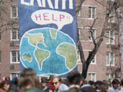 A crowd of people gather near a large poster that shows a speech bubble from planet Earth that reads &quot;Help!!&quot; on the occasion of the first Earth Day conservation awareness celebration, New York City, April 22, 1970.