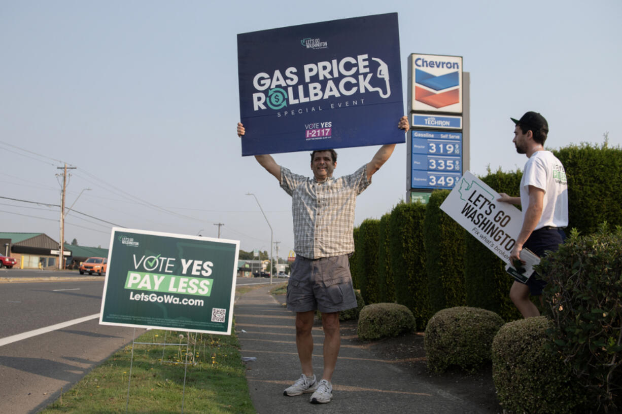 Phil Kronebush of Vancouver, left, joins Tim Lussier of Clackamas as they greet drivers outside a Chevron gas station along Northeast Andresen Road on Sept. 6. Let&rsquo;s Go Washington hosted three gas station events to highlight the I-2117 campaign. LGW slashed the cost of gasoline to reflect the national average and paid the difference on every gallon of gas sold during the event.