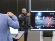 Attorney Matt Anderson, left, questions Seattle Police Officer Domisi Thrash during an inquest regarding the death of Kyle Gray Wednesday, Sept. 11, 2024, in the Chinook Building in Seattle. Gray was killed in December of 2017 and the inquest is finally taking place.  On the screen is dashboard footage from Officer Thrash&rsquo;s car when he was following Gray after a robbery. (Ellen M.