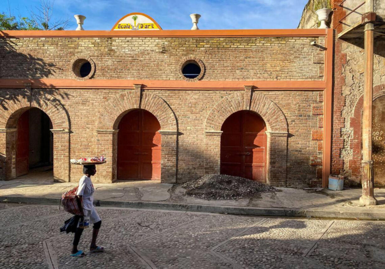 A woman walks by a building undergoing repairs in Jacmel, Haiti, where the tourism industry has taken a hit because of gang violence.