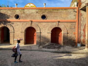 A woman walks by a building undergoing repairs in Jacmel, Haiti, where the tourism industry has taken a hit because of gang violence.