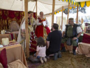 Abby Doty, 7, kneels alongside Brandon Bakemaeyer in a knighting ceremony presided over by Mary Stuart, Queen of Scots, at the 2023 Realms Unknown Fantasy Festival in Woodland. The historical reenactment group will return to this year&rsquo;s festival, which begins Friday and continues through Sunday.