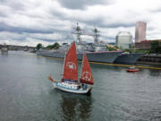 The Golden Rule historic sailboat glides past war ships in Portland June 2016 for Fleet Week.