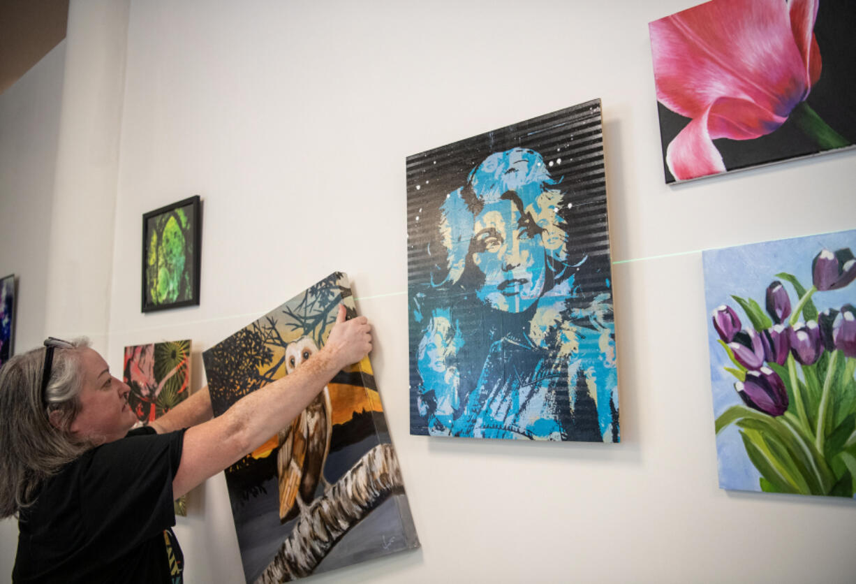 Christine A. Richardson, executive director of theARTScentered, hangs an owl painting Thursday at the Vancouver Arts Hub in the former Vancouver Community Library.