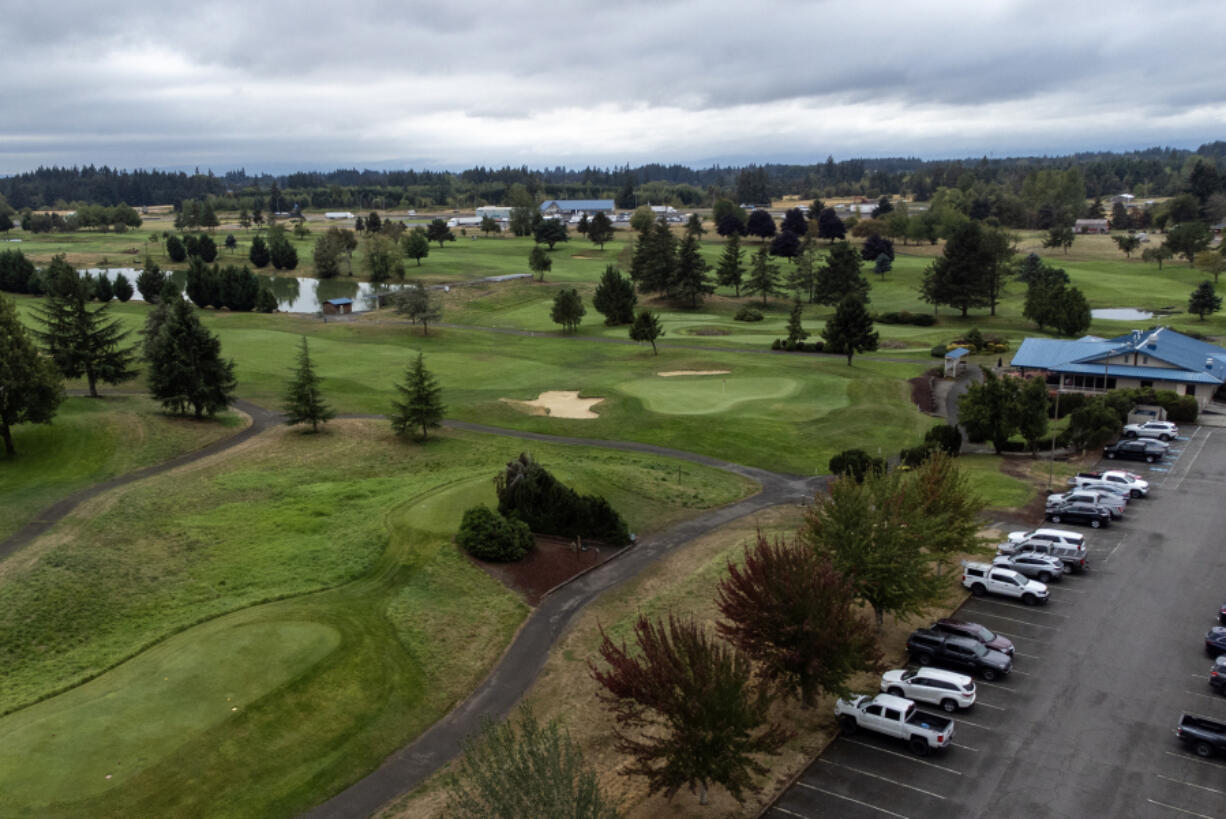 Cars sit in a parking lot next to the green Wednesday at Tri-Mountain Golf Course in Ridgefield. Clark County is putting the course up for sale later this month.