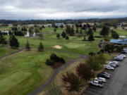 Cars sit in a parking lot next to the green Wednesday at Tri-Mountain Golf Course in Ridgefield. Clark County is putting the course up for sale later this month.