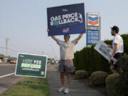 Phil Kronebush of Vancouver, left, joins Tim Lussier of Clackamas, Ore., as they greet drivers outside a Chevron gas station along Northeast Andresen Road on Friday morning. Let&rsquo;s Go Washington hosted three gas station events to highlight the Initiative 2117 campaign to repeal the state&rsquo;s Climate Commitment Act. The organization slashed the cost of gasoline to reflect the national average and paid the difference on every gallon of gas sold during the event.