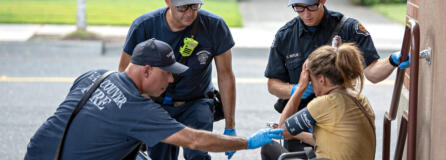 Jesse Martin, public information officer for the Vancouver Fire Department, from left, joins firefighter/engineer Paul Coulimore and firefighter/paramedic Caleb Butler as they assist a woman struggling during an excessive heat warning in Vancouver&rsquo;s Uptown Village on Thursday afternoon. The temperature was hovering near triple digits at the time of the call.