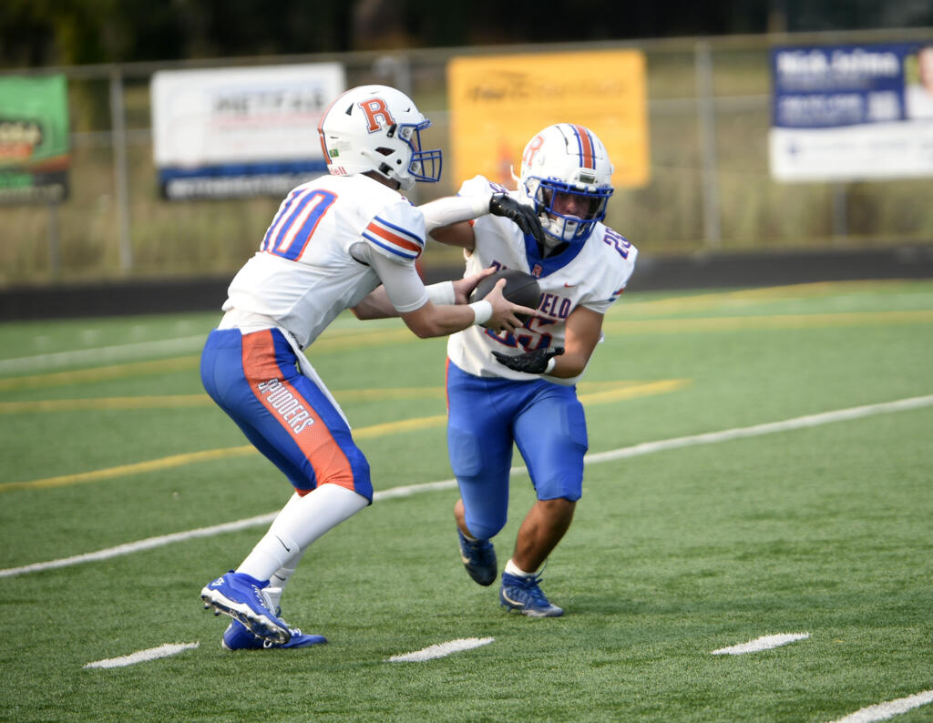 Landon DeBeaumont (10) of Ridgefield fakes a handoff to Cly Stephens (25) against Prairie during a non-league football game at District Stadium in Battle Ground on Saturday, Sept. 7, 2024.