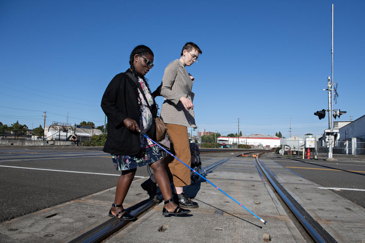 Vancouver resident Abby Griffith, left, who is blind, navigates train tracks while leaving the Vancouver train station with Kail Hibbs of the city of Vancouver on Monday afternoon. The journey took place ahead of the city&rsquo;s Week Without Driving challenge to highlight the importance of mobility access in the region.