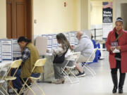 FILE - A woman walks with her ballot to a vacant voting booth at City Hall in San Francisco, March 5, 2024.