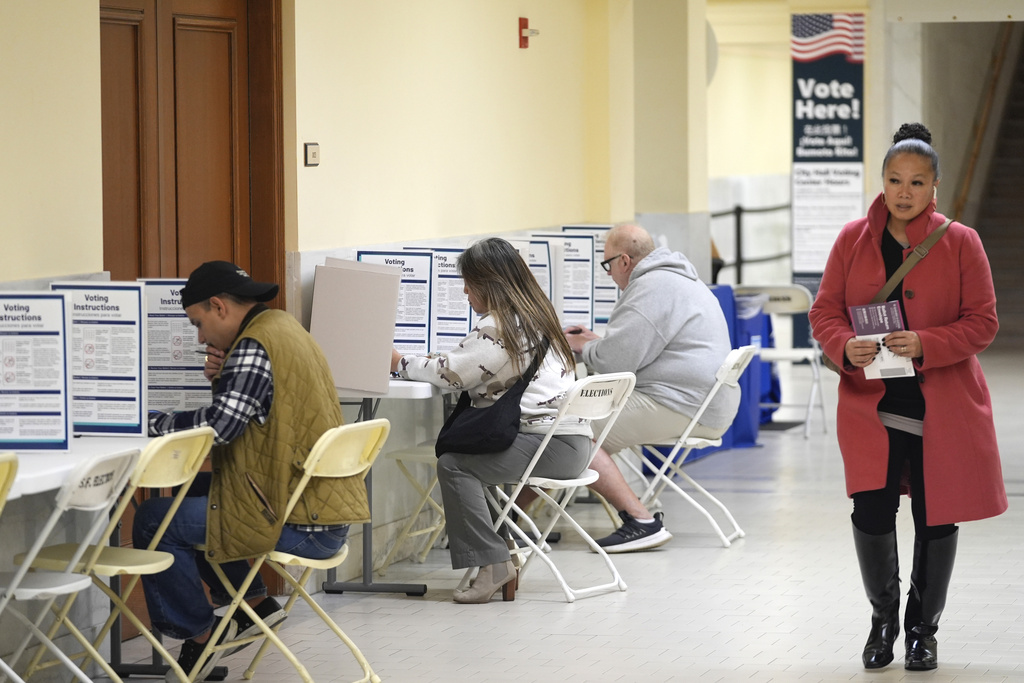 FILE - A woman walks with her ballot to a vacant voting booth at City Hall in San Francisco, March 5, 2024.