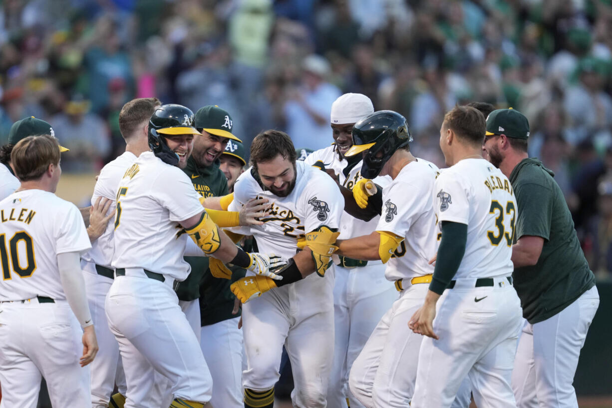 Oakland Athletics' Shea Langeliers, center, is mobbed by teammates after hitting a winning solo home run against the Seattle Mariners in a baseball game Monday, Sept. 2, 2024, in Oakland, Calif. (AP Photo/Godofredo A.