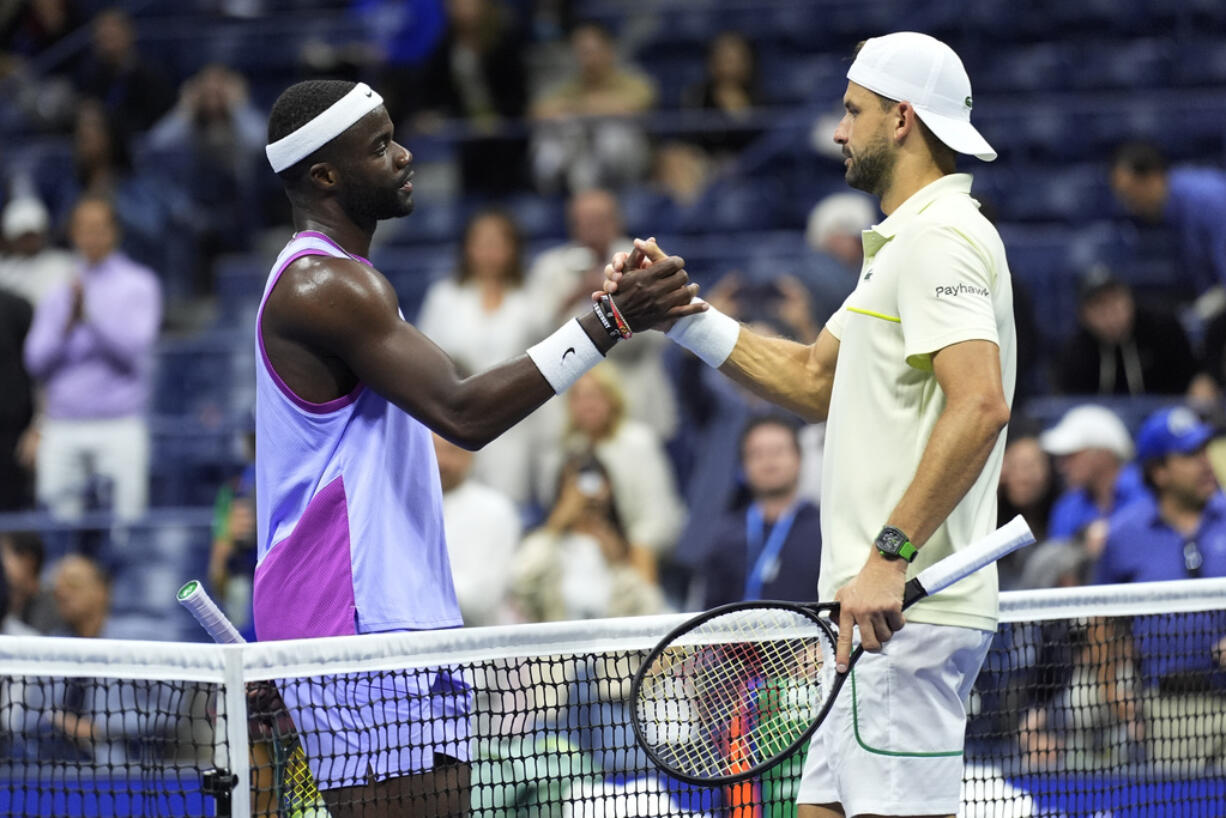 Grigor Dimitrov, of Bulgaria, right, shakes hands with Frances Tiafoe, of the United States, after he was forced to retire due to an apparent injury during the quarterfinals of the U.S. Open tennis championships, Tuesday, Sept. 3, 2024, in New York.