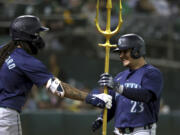 Seattle Mariners' Luis Urías (23) celebrates with J.P. Crawford (3) after hitting a home run against the Oakland Athletics during the seventh inning of a baseball game in Oakland, Calif., Wednesday, Sept. 4, 2024.